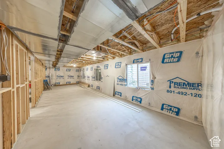 Unfinished lower level featuring exposed wood framing, concrete flooring, metallic ductwork, and egress-style windows