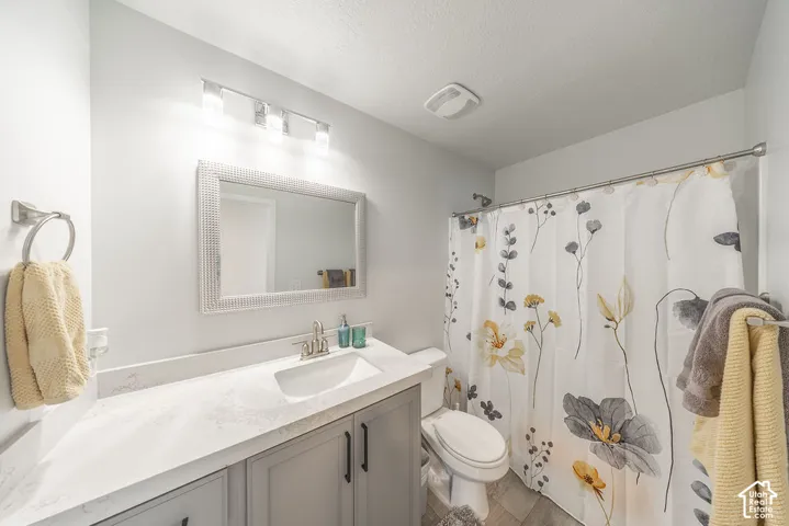 Bathroom featuring a vanity with grey cabinetry, a solid-surface countertop with an integrated basin, a rectangular framed mirror, a multi-bulb light fixture, and a shower-tub combination