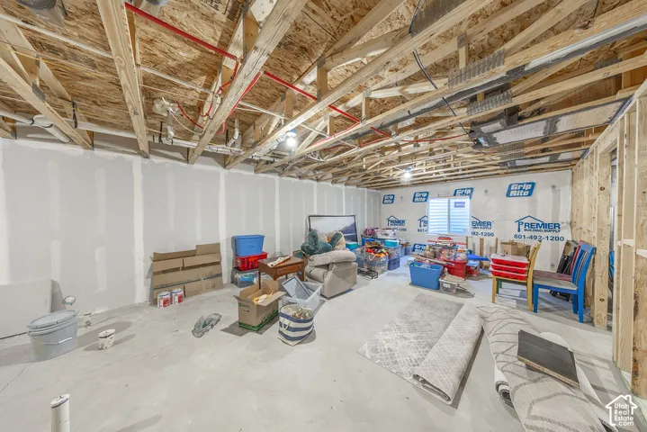 Unfinished space featuring exposed timber framing, concrete flooring, drywall-ready walls, and plumbing infrastructure