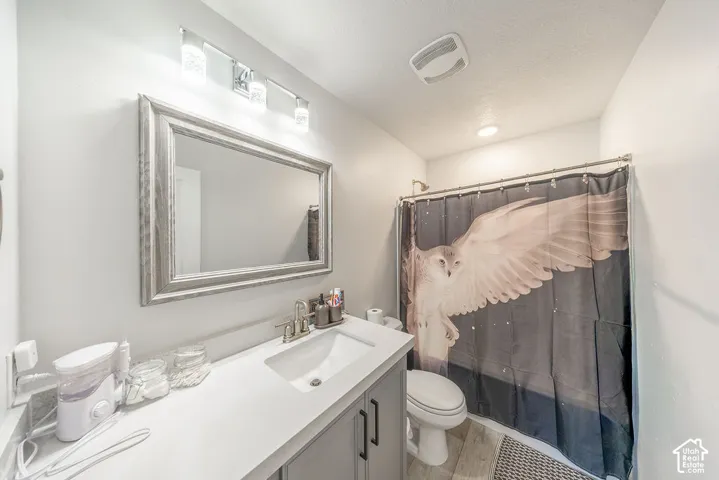Bathroom featuring a vanity with a white countertop and rectangular undermount sink, gray cabinetry with dark hardware, a framed mirror, a multi-bulb light fixture, and a shower-tub combination