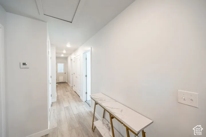 Hallway featuring light-toned wood-finish flooring, recessed lighting, and white panel doors