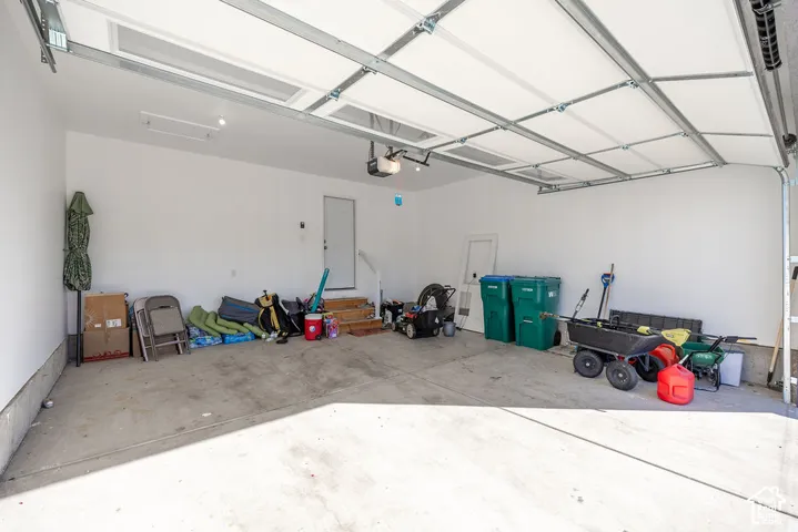 Attached garage featuring a concrete floor, white interior walls, an automated overhead door with integrated windows, and a dedicated service door with stairs