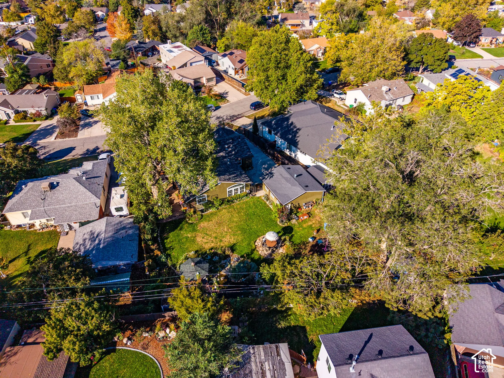 Aerial perspective featuring an expansive lawn, mature shade trees, and defined hardscaping within a residential setting