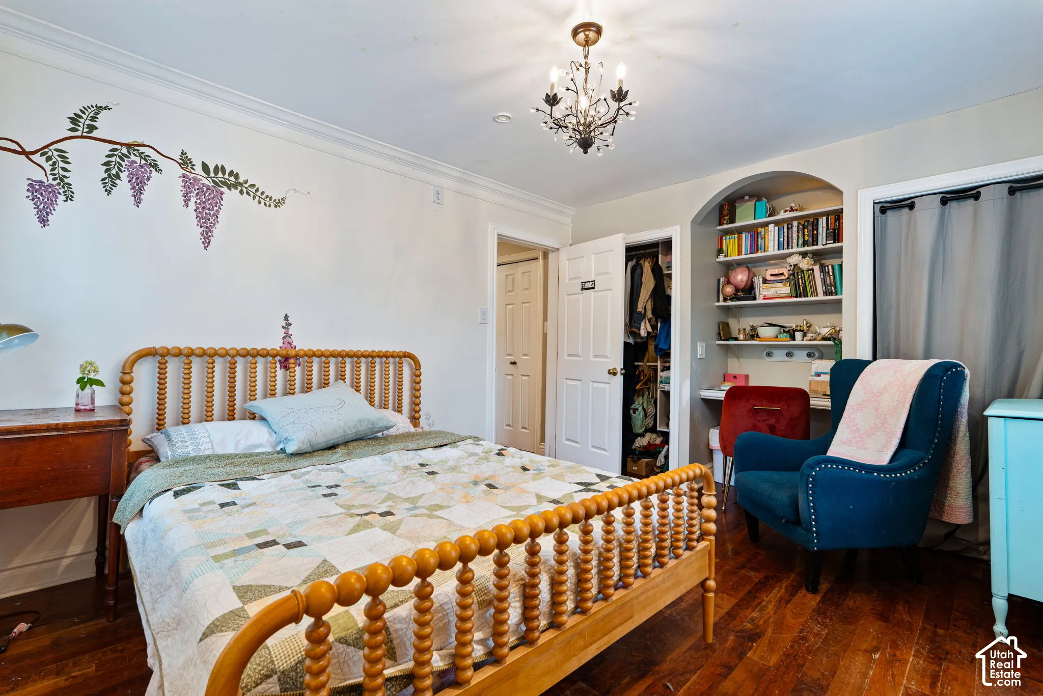Room featuring dark wood-finish flooring, a traditional metal chandelier, a built-in arched alcove with shelving and a desk surface, and a closet with a six-panel door