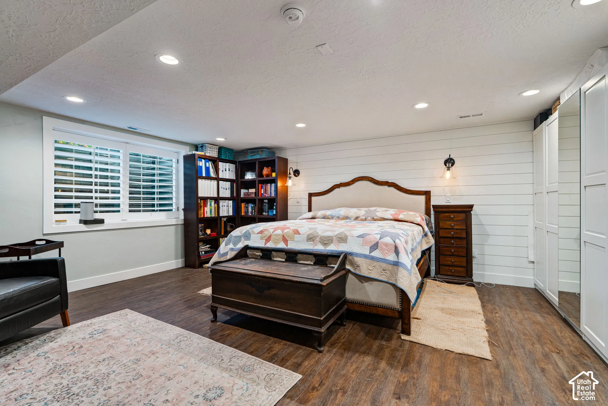 Room featuring wood-finish flooring, recessed lighting, horizontal shiplap wall paneling, plantation shutters, and floor-to-ceiling mirrored closet doors
