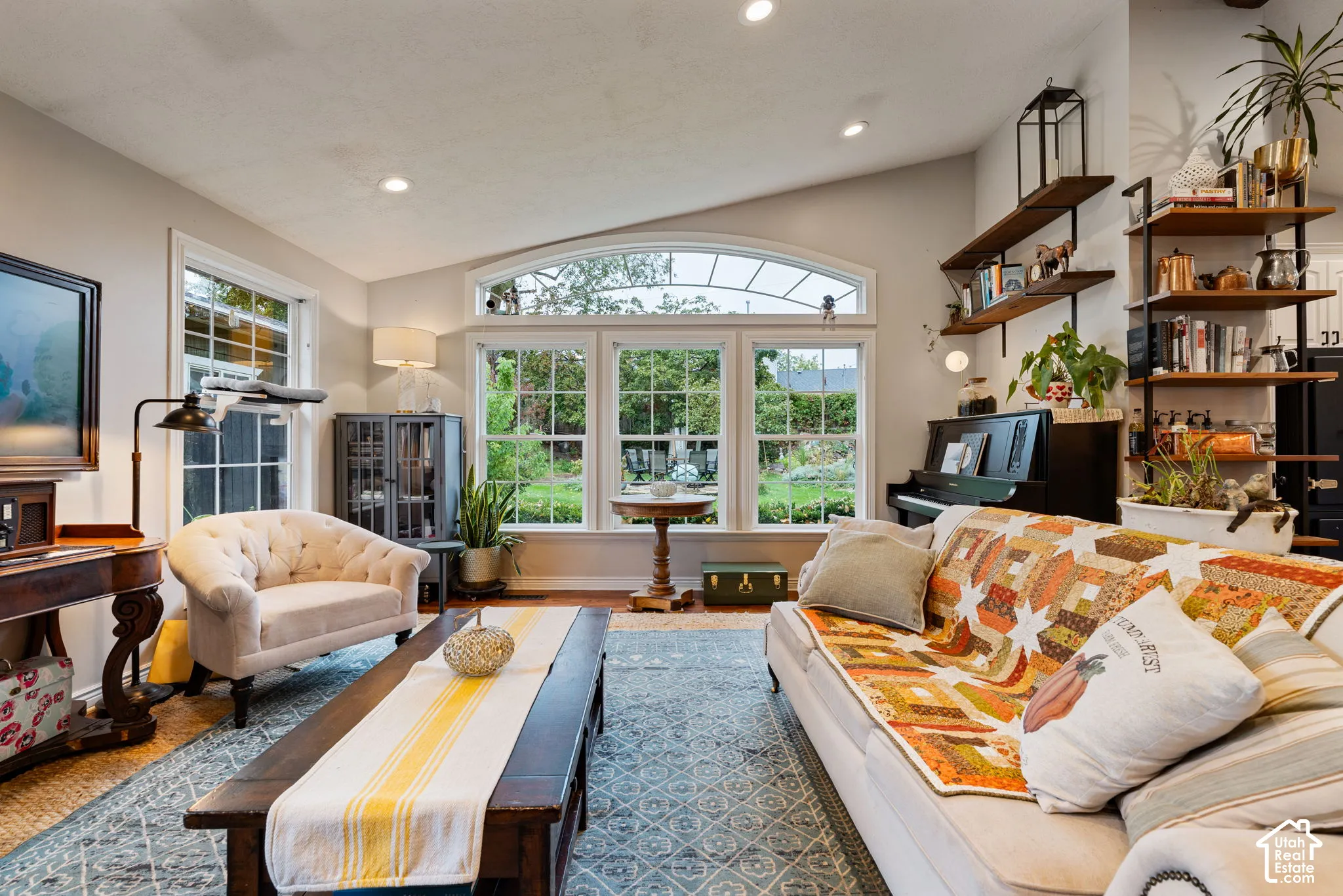 Vaulted ceiling featuring recessed lighting, large multi-pane windows with arched transom, and wall-mounted wood shelving