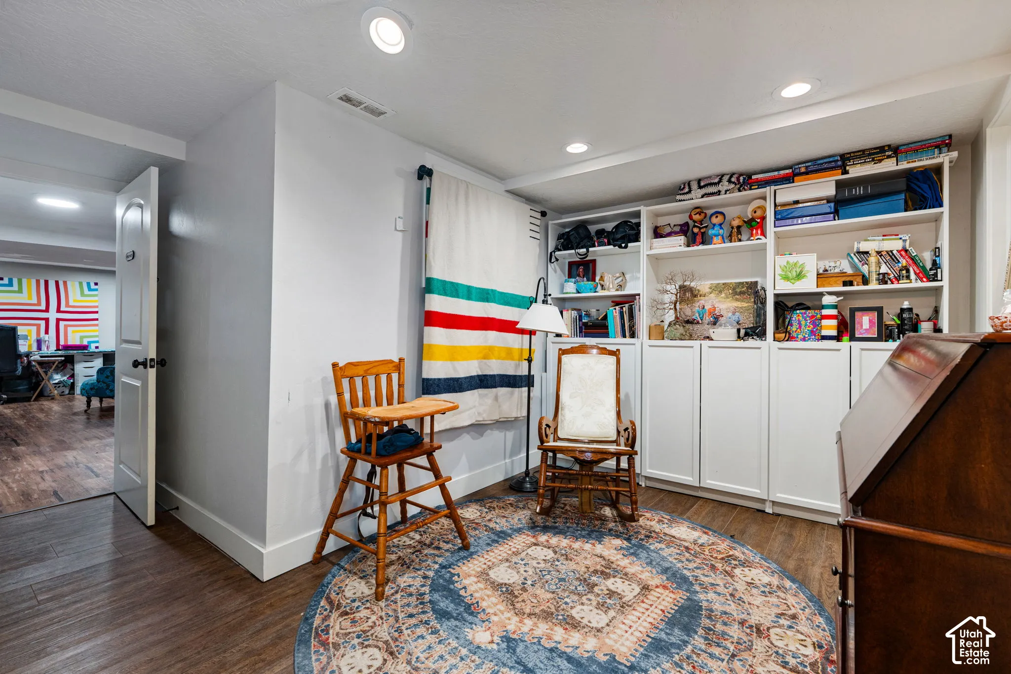 Built-in floor-to-ceiling white cabinetry with open shelving and closed storage, wood-finish flooring, and recessed ceiling lighting