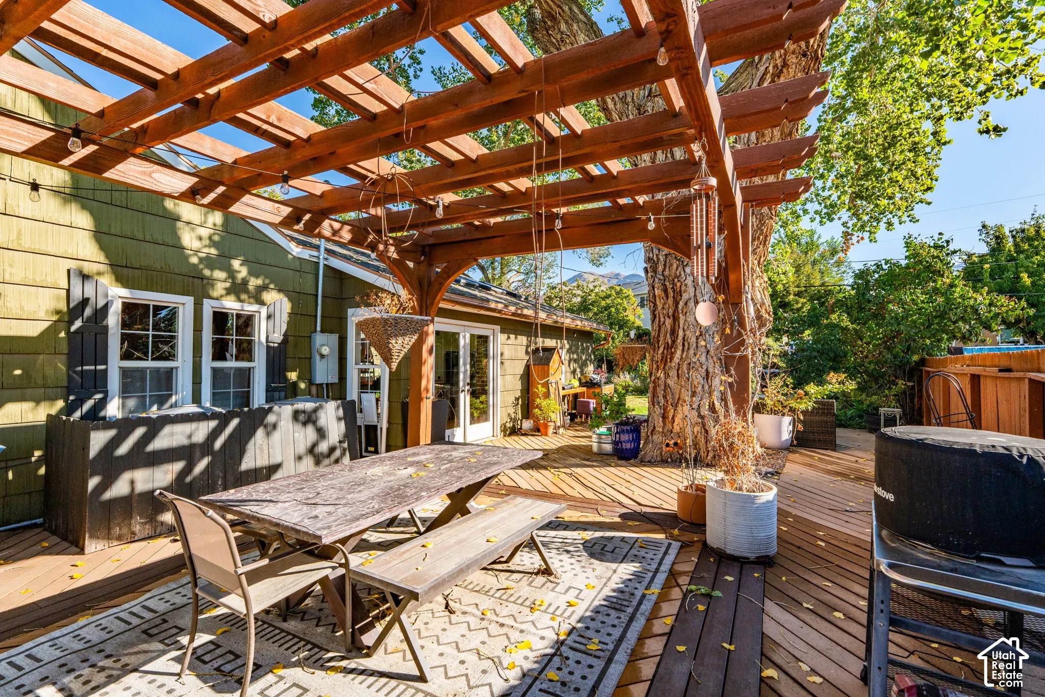 Outdoor wood pergola structure covering a spacious wood deck, featuring cedar-style siding and glass-paneled double doors