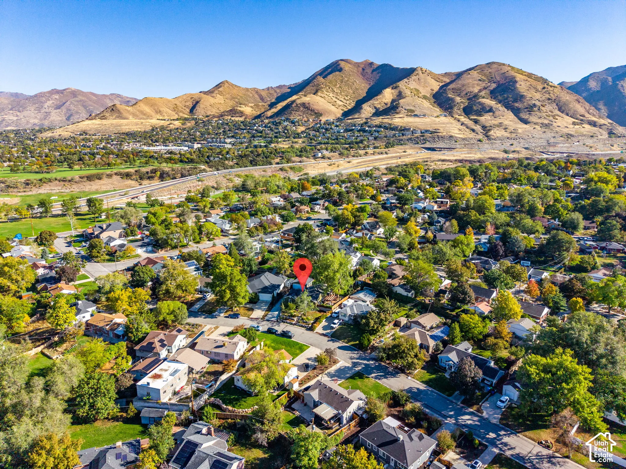 Aerial perspective featuring mature trees, a manicured lawn, and mountain scenery