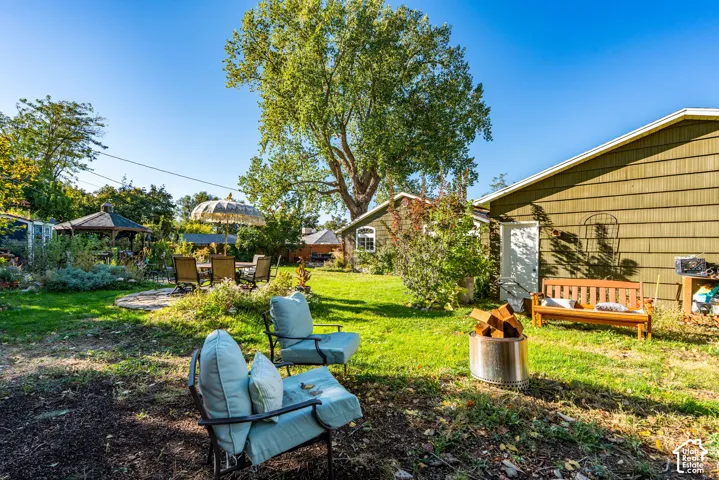 Backyard featuring mature trees, a lawn, a stone-paved patio, and an outdoor gazebo