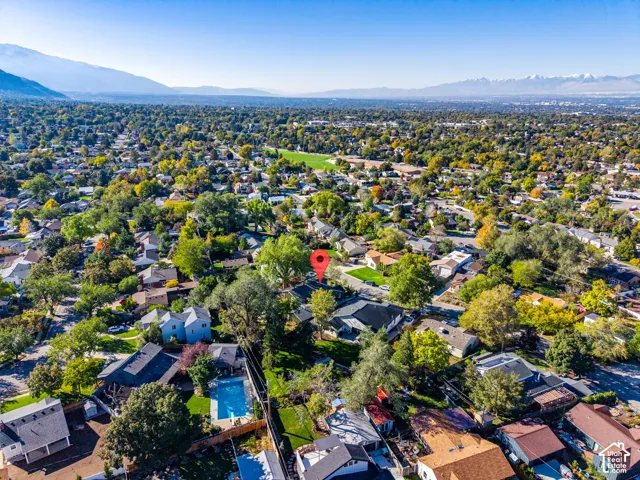 Aerial perspective featuring a residential property with a private in-ground swimming pool, set against a backdrop of distant mountain ranges and expansive mature foliage