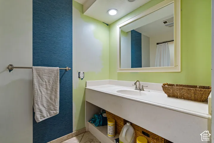 Vanity featuring a white countertop with an integrated basin, chrome-finish faucet, recessed lighting, and a framed wall mirror