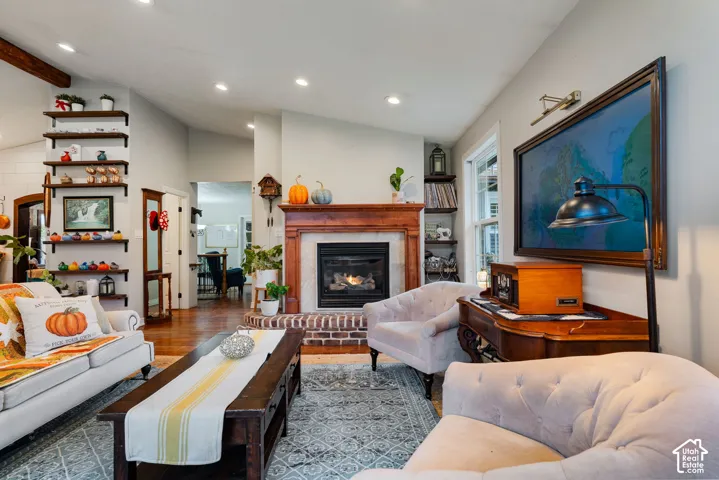 Fireplace with a wood mantle and brick hearth, recessed ceiling lighting, wood-finish flooring, and integrated wall shelving