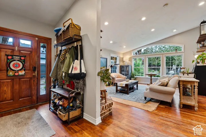 Entryway featuring a solid wood front door with glass sidelights, wood-finish flooring, recessed lighting, and a brick-accented partition wall