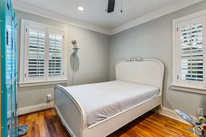 Wood-finish flooring, white plantation shutters, crown molding, recessed lighting, and a ceiling-mounted fan