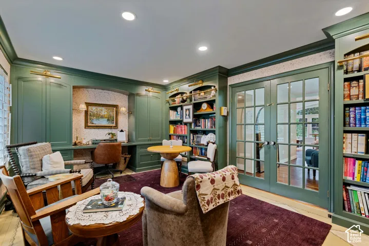 Custom built-in green cabinetry with integrated bookshelves, recessed lighting, brass hardware, and French doors featuring glass panes