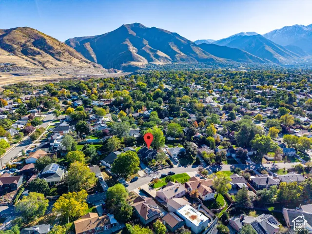 Aerial perspective featuring mature trees, established landscaping, and prominent mountain backdrops