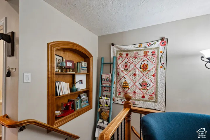 In-wall wooden arched shelving unit, wooden handrail with turned baluster, and wall-mounted light fixture