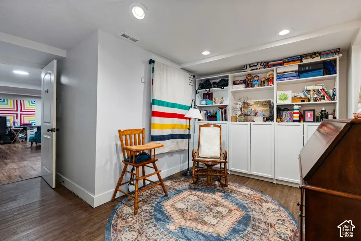 Built-in floor-to-ceiling white cabinetry with open shelving and closed storage, wood-finish flooring, and recessed ceiling lighting