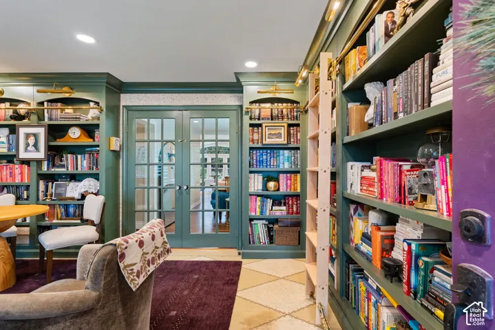 Floor-to-ceiling built-in cabinetry with integrated library lighting, rolling library ladder, and French doors