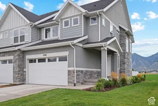 Multi-level exterior featuring stone veneer accents, horizontal siding, dual-gabled rooflines, and a mountain backdrop