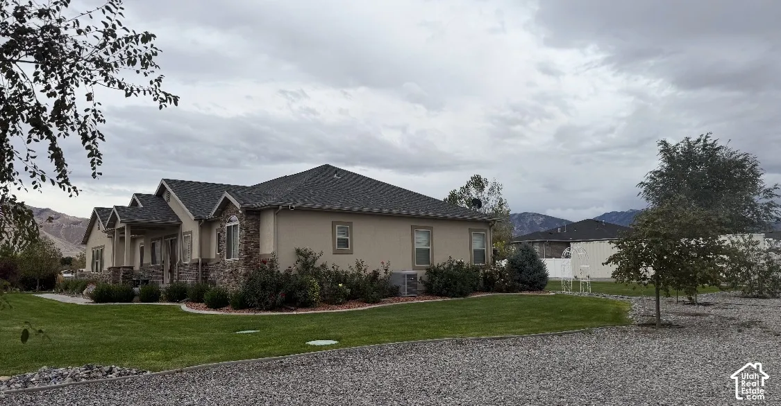 Single-story residence featuring stone and stucco exterior, multi-gabled roofline, manicured lawn, and professional landscaping