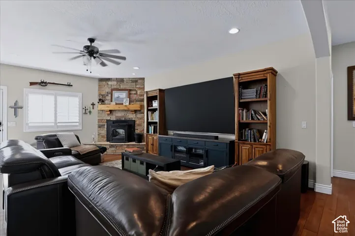 Corner stone-surround fireplace with wood-finish mantel, built-in wooden cabinetry, plantation shutters, and wood-finish flooring