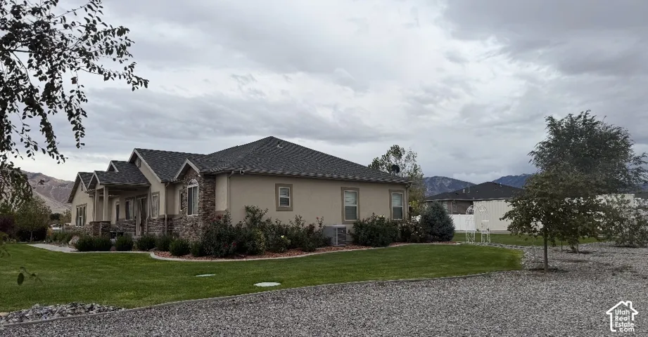 Single-story residence featuring stone and stucco exterior, multi-gabled roofline, manicured lawn, and professional landscaping