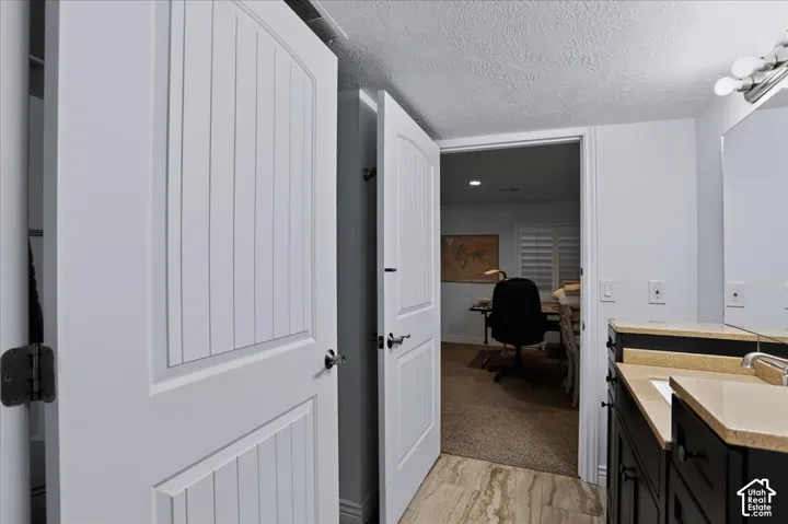 Bathroom featuring a dark wood-finish vanity with a stone countertop, an integrated rectangular sink, wall-mounted mirror, and multi-bulb vanity lighting