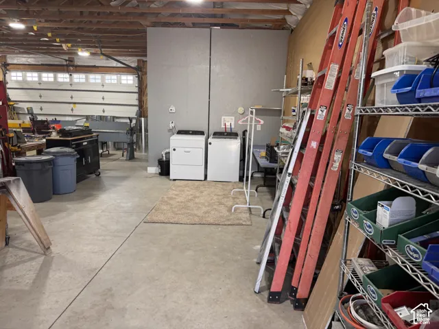 Multi-purpose workshop space featuring exposed wood-beam ceiling, concrete flooring, and a dedicated laundry area