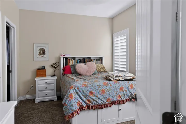 Neutral-toned bedroom featuring white plantation shutters and built-in storage cabinetry