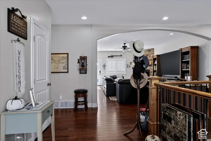 Interior space featuring wood-finish flooring, a decorative arched entryway, recessed lighting, and a stone-accented hearth