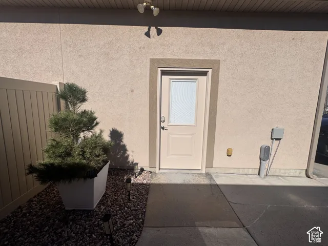 Stucco exterior featuring a solid door with a glass insert, concrete walkway, and gravel landscaping