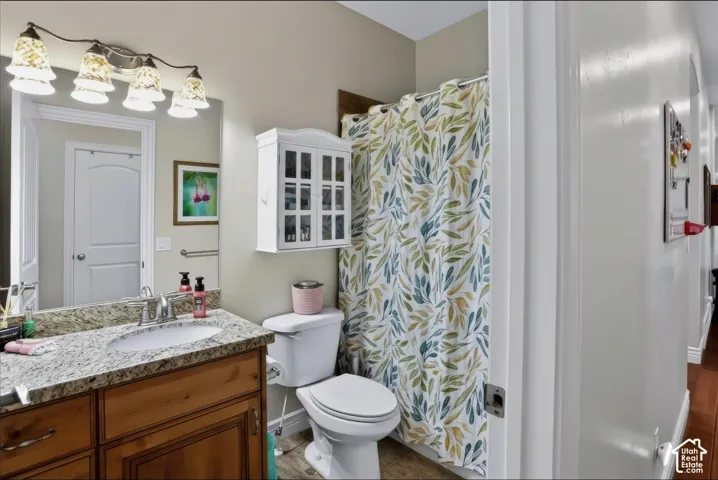 Bathroom featuring a stone-look countertop, wood-finish cabinetry, wall-mounted storage cabinet, and a four-light fixture