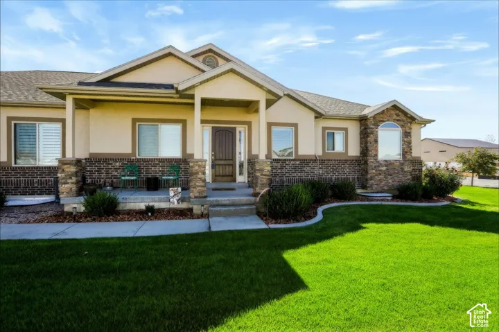 Exterior featuring a combination of brick and stone masonry, arched window detail, covered front porch, and manicured lawn