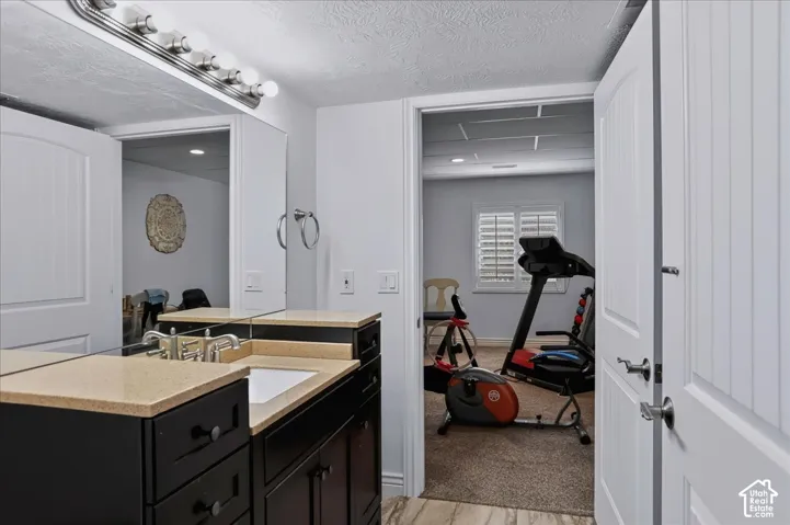 Dark-toned vanity with integrated stone countertop and rectangular undermount sink, illuminated by a multi-bulb vanity light fixture