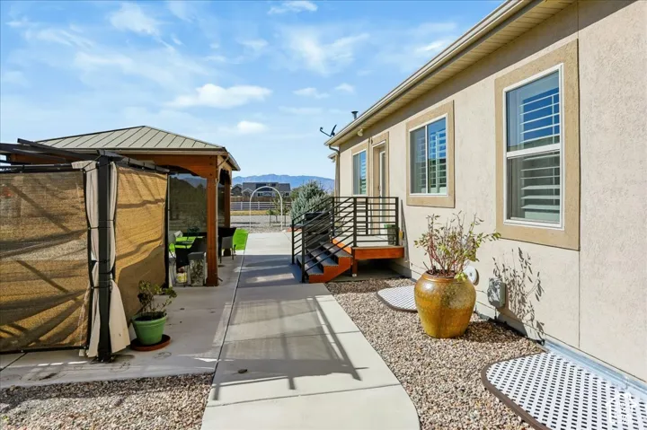 Exterior space featuring a metal-roofed gazebo, concrete patio, gravel landscaping, and a staircase with black horizontal railings