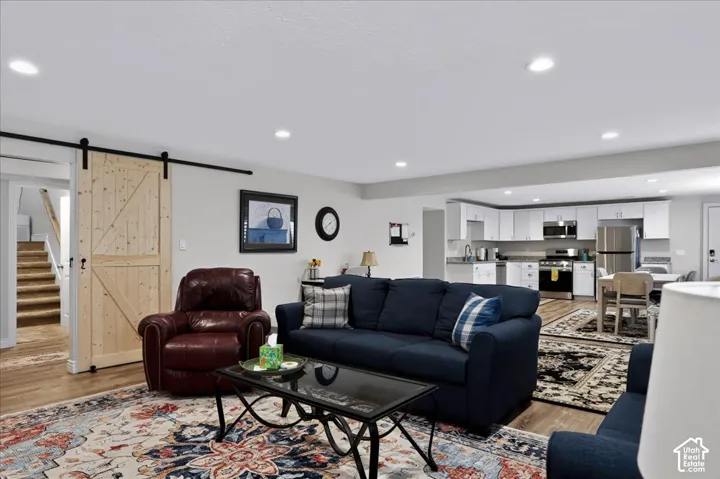 Open-concept living space featuring wood-finish flooring, recessed lighting, and a natural-finish sliding barn door