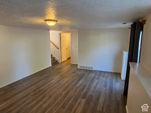 Spacious open living area with wood-finish flooring, recessed ceiling lighting, and abundant natural light from large windows with horizontal blinds