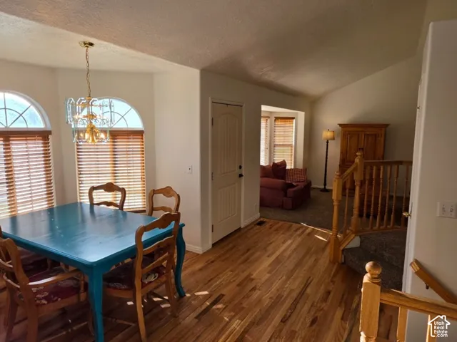 Hardwood flooring, vaulted ceiling, arched transom windows, and a chandelier-style light fixture