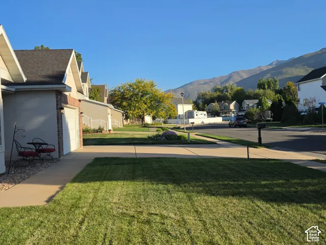 Manicured front lawn, concrete walkway, stucco exterior, arched window detail, attached garage