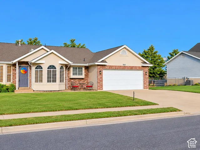 Tan stucco and brick facade with arched windows, an attached two-car garage, and a concrete driveway