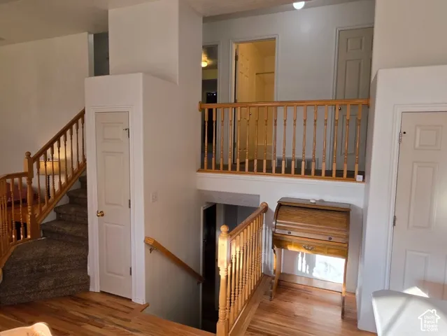 Multi-level interior featuring wood-finish flooring, carpeted stairs, and wood balusters