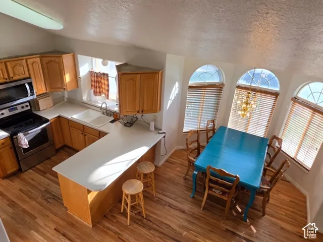 Kitchen featuring wood-finish cabinetry, stainless steel appliances, and L-shaped white countertops