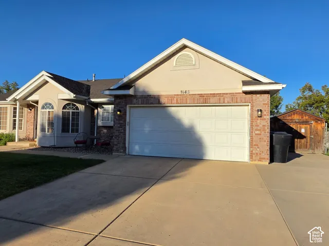 Stucco and brick exterior with arched window details, an attached garage, and a concrete driveway