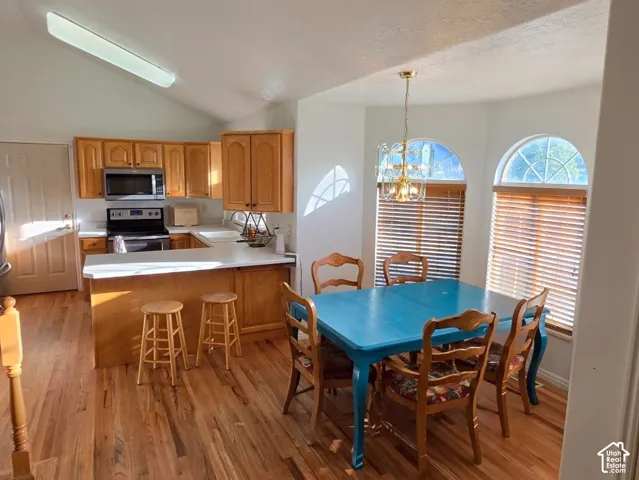 Kitchen and dining area featuring wood-finish flooring, vaulted ceilings, and light wood cabinetry