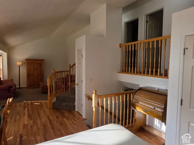 Wood-finish flooring, vaulted ceiling, white walls, and wood railings