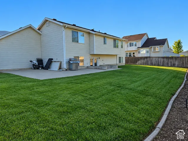 Expansive backyard featuring a concrete patio, wood fence, and a storage shed