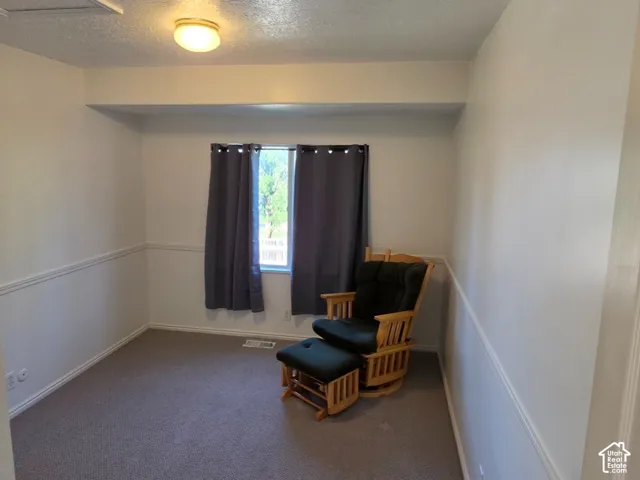 Carpeted room featuring a single window and wainscoting