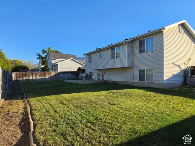 Spacious backyard featuring a manicured lawn, wood fencing, and a concrete patio